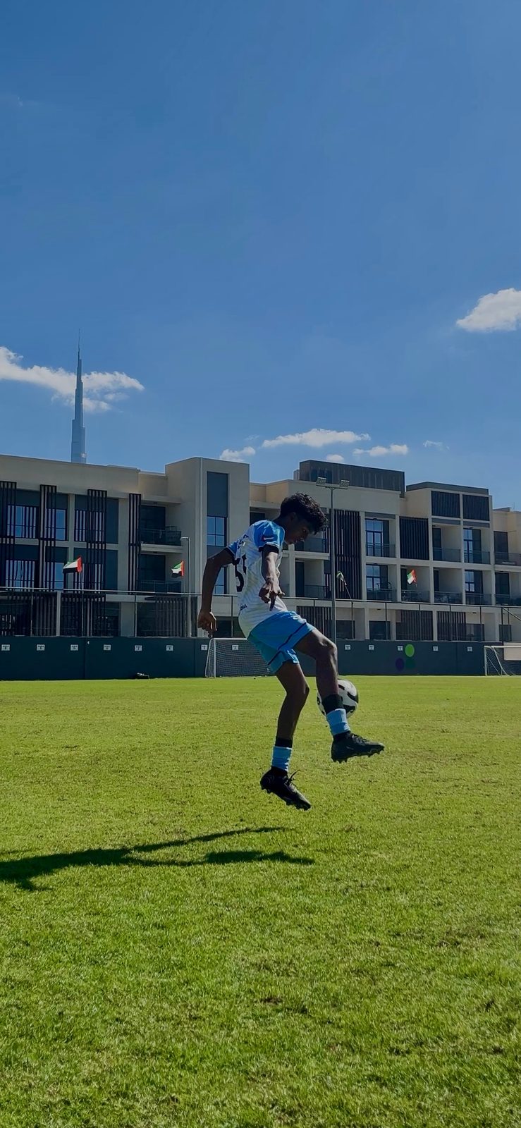 Dev juggling a football with the Burj Khalifa in the background