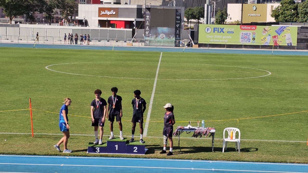 Dev standing first on the athletics podium at a stadium medal ceremony